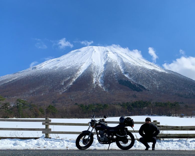 大山まきばみるくの里から撮る雪景色の中の左右対称の大山とバイクと人